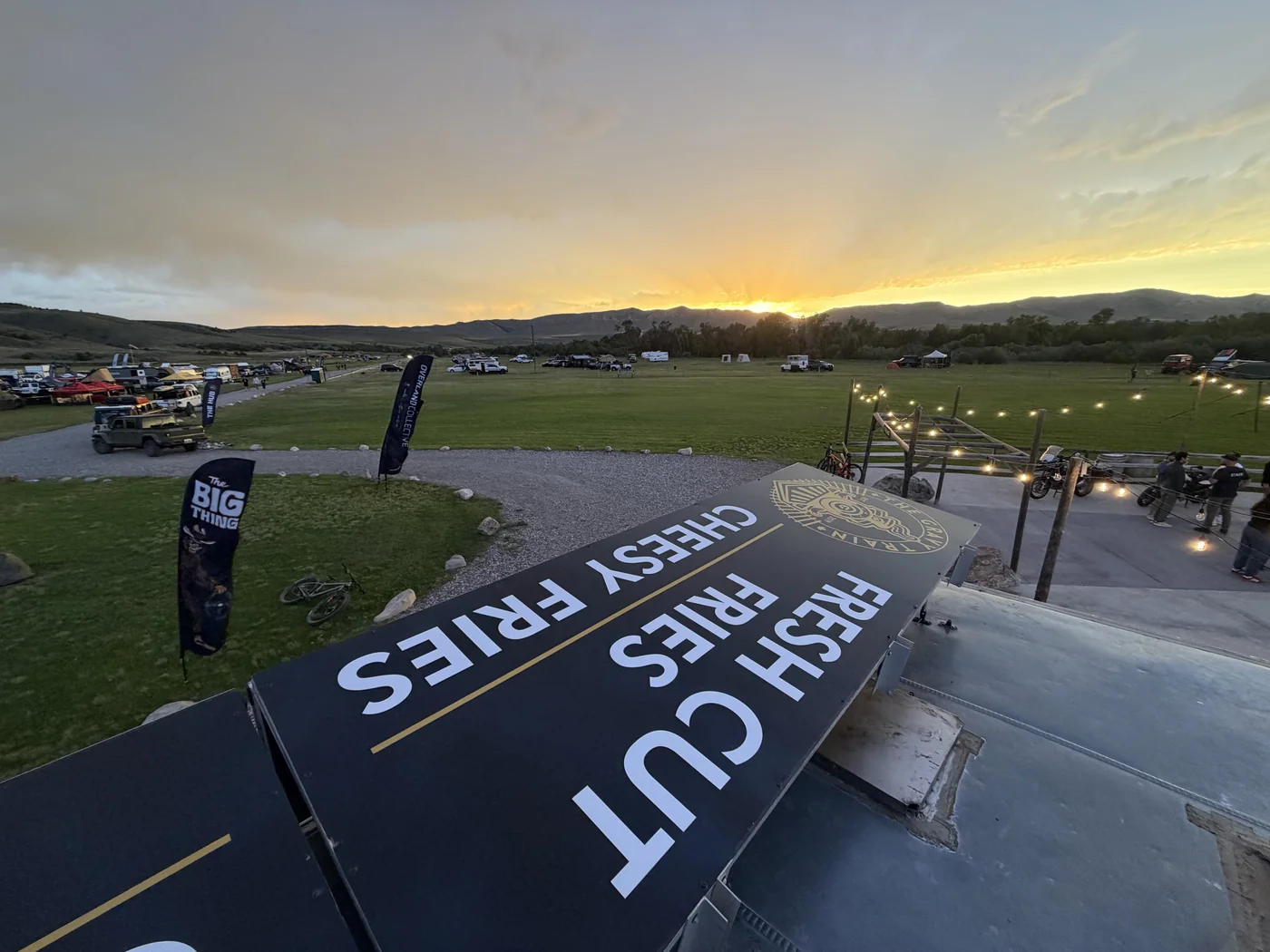 Overland rigs and camps at sunset with The Big Thing event banner at XOverland Ranch