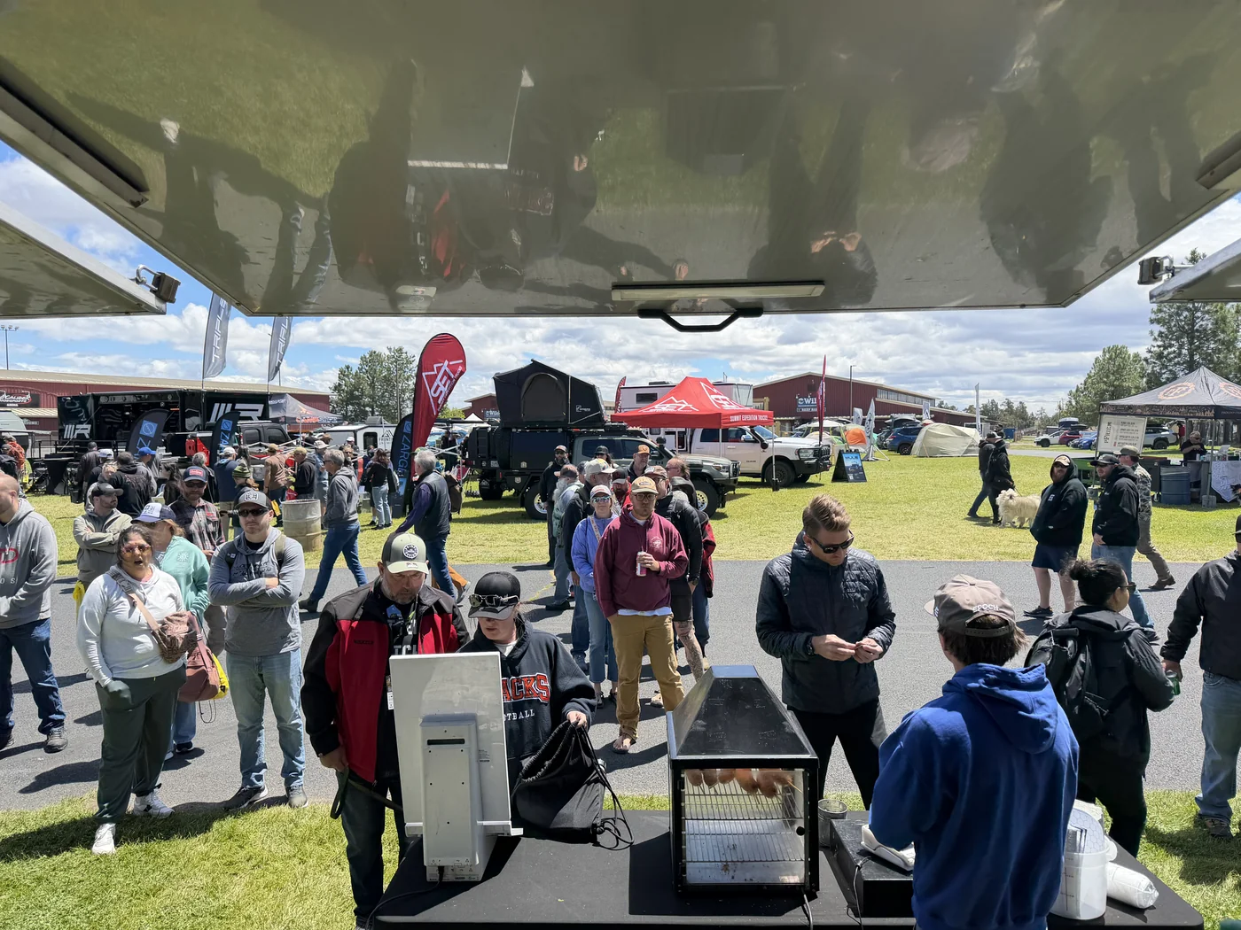 Packed crowd at Overland Expo PNW with overlanding rigs and vendor tents